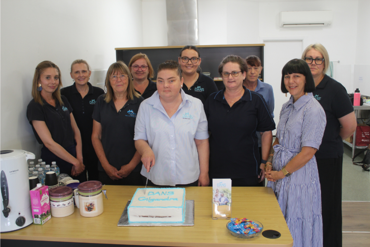 Dubbo care manager Lisa joined Gilgandra care staff Bronwyn, Karen, Halina, Chloe, Gaye, Brenda, as well as chief operating officer Briette and Dubbo senior care manager Kelly; (centre) Gilgandra care manager Emma offered to cut the cake. Photo by The Gilgandra Weekly: Nicholas Croker.